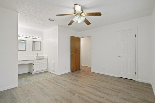 1926 Klauke Ct, Rosenberg, TX 77471 - unfurnished bedroom featuring light wood-type flooring, a sink, baseboards, ensuite bathroom, and ceiling fan