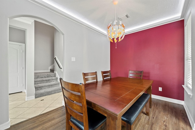 dining room with a chandelier, arched walkways, stairs, and baseboards