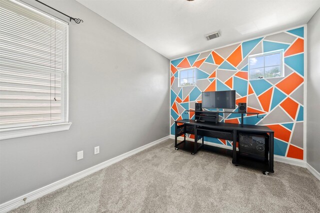 carpeted home office with an accent wall, baseboards, and plenty of natural light