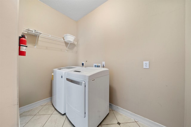 washroom with light tile patterned floors, separate washer and dryer, and baseboards