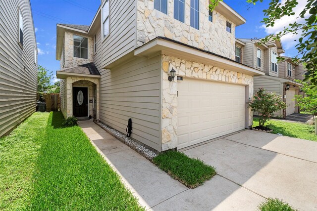 view of front of house with stone siding, a garage, concrete driveway, and a front yard