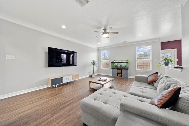 living room featuring wood finished floors, a ceiling fan, recessed lighting, baseboards, and crown molding