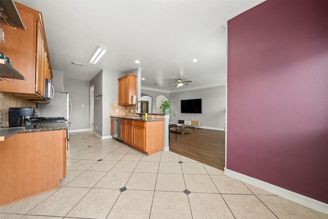 kitchen featuring stainless steel appliances, open floor plan, tasteful backsplash, light tile patterned floors, and brown cabinetry