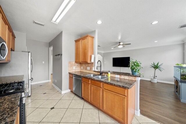 kitchen featuring a sink, stainless steel appliances, a ceiling fan, a peninsula, and light tile patterned floors