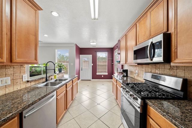 kitchen featuring stainless steel appliances, a sink, backsplash, baseboards, and recessed lighting