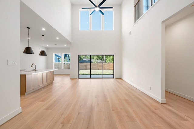 1420 Flamingo St, Conroe, TX 77385 - unfurnished living room with a towering ceiling, light wood-type flooring, a sink, baseboards, and recessed lighting