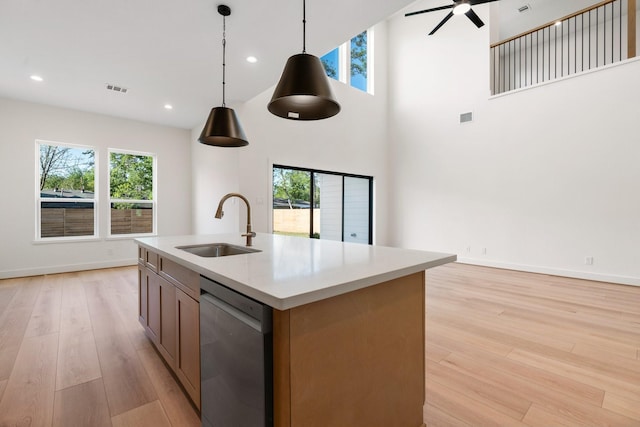 1420 Flamingo St, Conroe, TX 77385 - kitchen featuring stainless steel dishwasher, a sink, light wood-style floors, decorative light fixtures, and light countertops