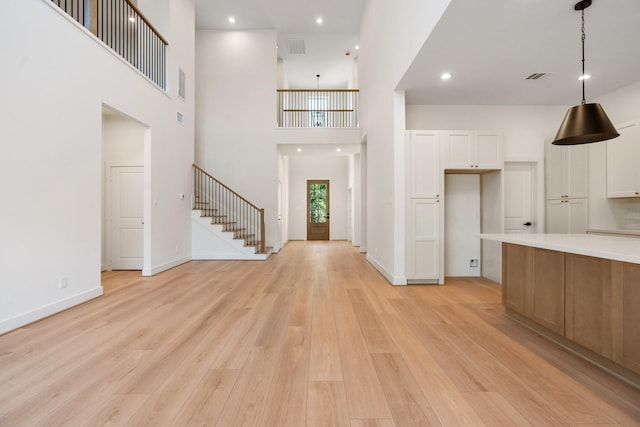 entrance foyer featuring light wood-style floors, stairs, a high ceiling, baseboards, and recessed lighting