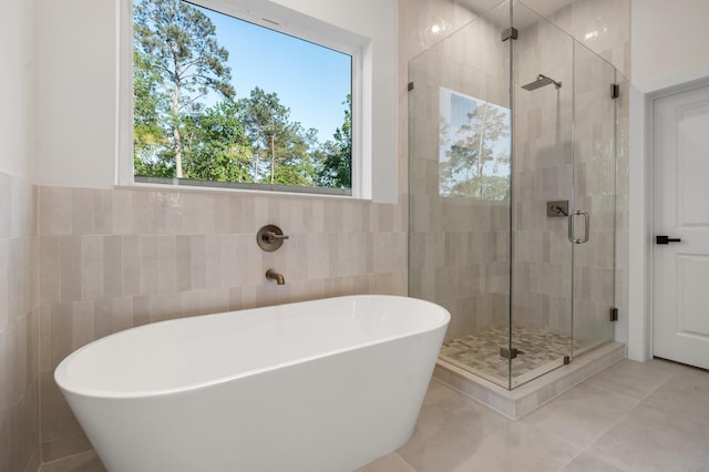 1420 Flamingo St, Conroe, TX 77385 - bathroom featuring tile walls, healthy amount of natural light, a freestanding tub, a shower stall, and tile patterned floors