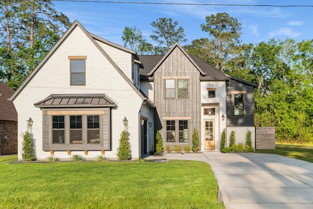 view of front of property featuring a front lawn, brick siding, concrete driveway, a standing seam roof, and board and batten siding