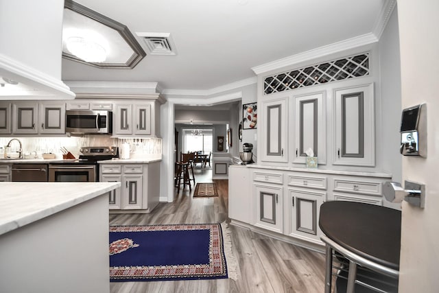 5050 Woodway Dr Unit 7L, Houston, TX 77056 - kitchen with stainless steel appliances, wood finished floors, backsplash, a sink, and ornamental molding