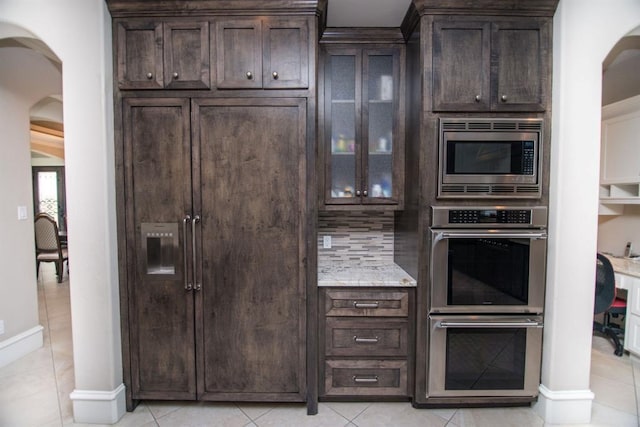 14115 Woodthorpe Ln, Houston, TX 77079 - kitchen featuring stainless steel appliances, arched walkways, dark brown cabinets, and light tile patterned floors