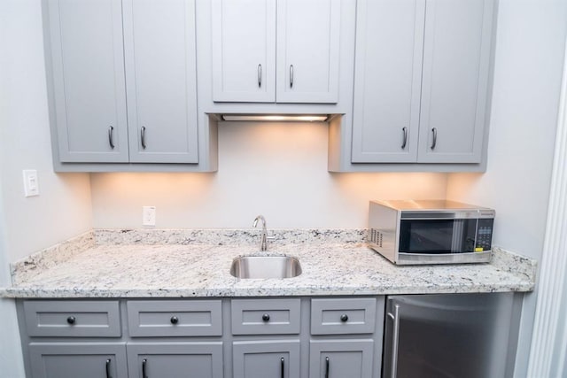 14115 Woodthorpe Ln, Houston, TX 77079 - kitchen with stainless steel microwave, gray cabinets, a sink, fridge, and light stone counters