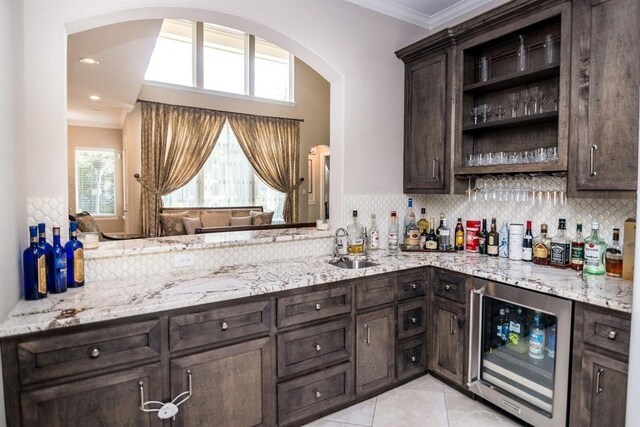 14115 Woodthorpe Ln, Houston, TX 77079 - indoor dry bar featuring beverage cooler, crown molding, arched walkways, plenty of natural light, and light tile patterned floors
