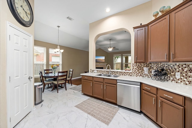 kitchen with stainless steel dishwasher, a sink, light marble finish floors, pendant lighting, and backsplash