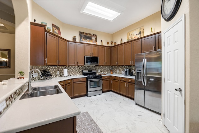 kitchen featuring appliances with stainless steel finishes, a sink, light marble finish floors, and light countertops