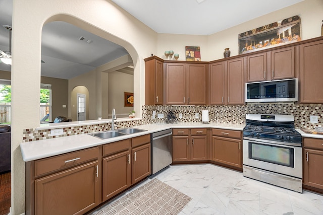 kitchen featuring appliances with stainless steel finishes, arched walkways, a sink, light marble finish flooring, and light countertops