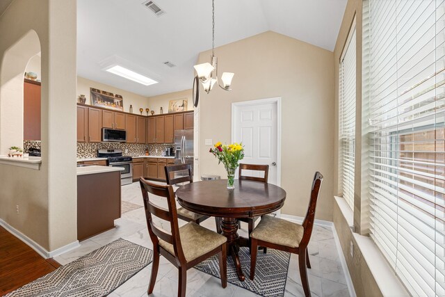 dining room featuring a chandelier, lofted ceiling, and light marble finish flooring