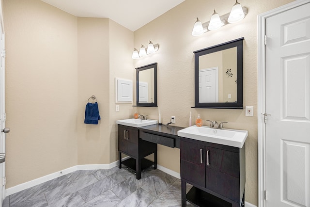 full bath featuring two vanities and baseboards