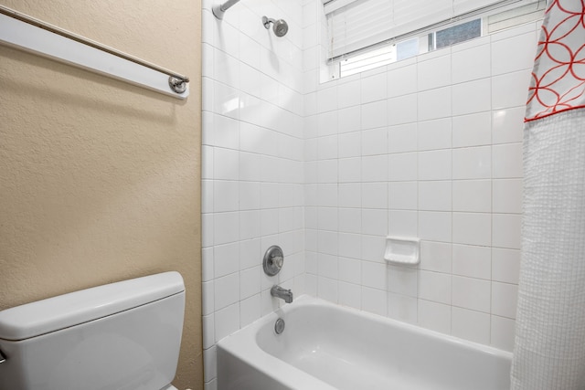 full bathroom featuring a textured wall, shower / bath combination with curtain, and toilet