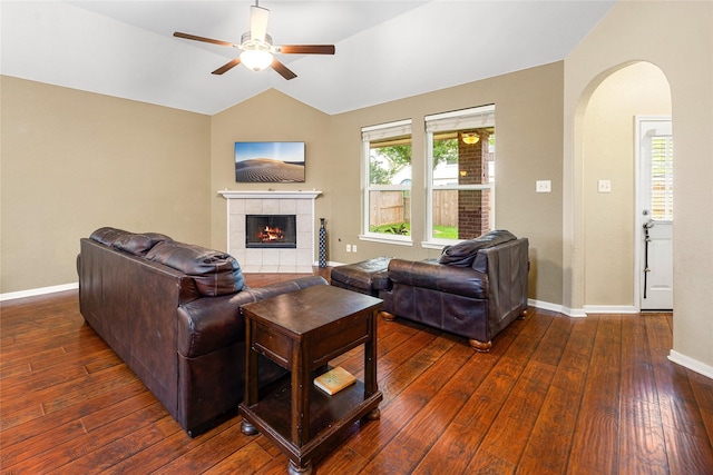 living area with arched walkways, a ceiling fan, wood-type flooring, lofted ceiling, and a fireplace