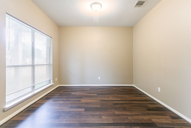empty room featuring dark wood finished floors, baseboards, and a textured ceiling