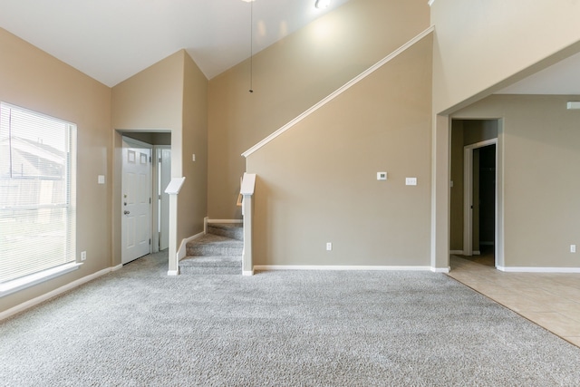 unfurnished living room featuring carpet flooring, stairway, baseboards, and high vaulted ceiling