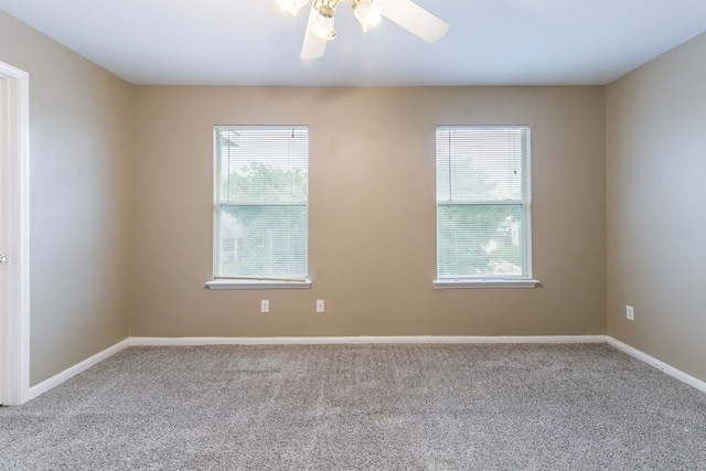 carpeted spare room featuring healthy amount of natural light, a ceiling fan, and baseboards