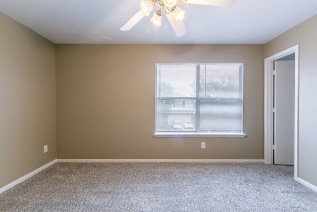 carpeted spare room with a ceiling fan and baseboards