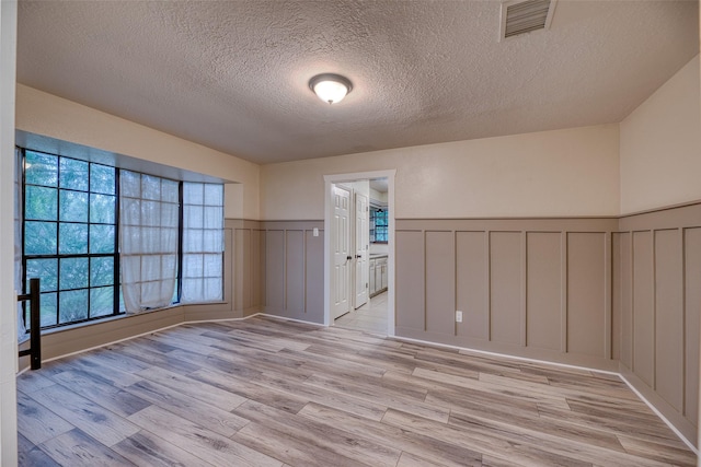 4650 Hickory Downs Dr, Houston, TX 77084 - spare room featuring a decorative wall, a textured ceiling, light wood finished floors, and wainscoting