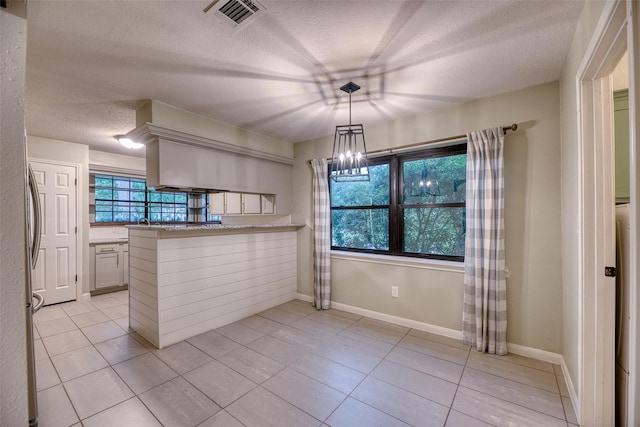 4650 Hickory Downs Dr, Houston, TX 77084 - kitchen featuring a textured ceiling, light tile patterned floors, a peninsula, a chandelier, and baseboards