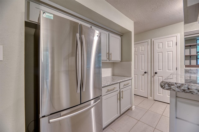 4650 Hickory Downs Dr, Houston, TX 77084 - kitchen with freestanding refrigerator, light tile patterned floors, backsplash, a textured ceiling, and light stone counters