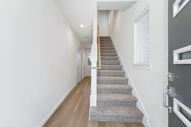 stairway with wood finished floors, recessed lighting, and baseboards