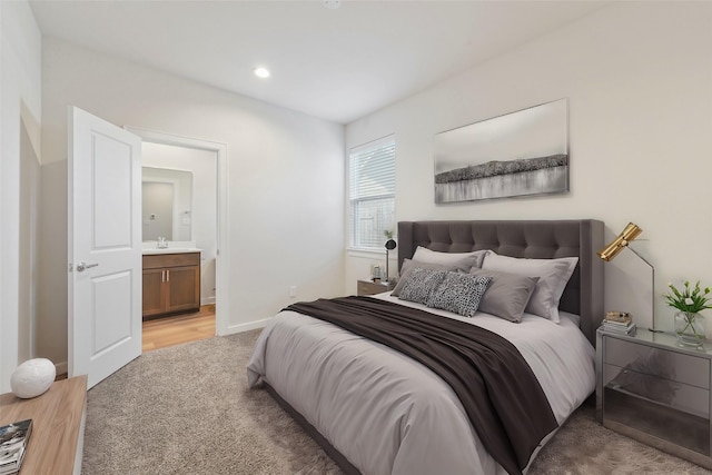 bedroom with light carpet, ensuite bathroom, a sink, recessed lighting, and baseboards