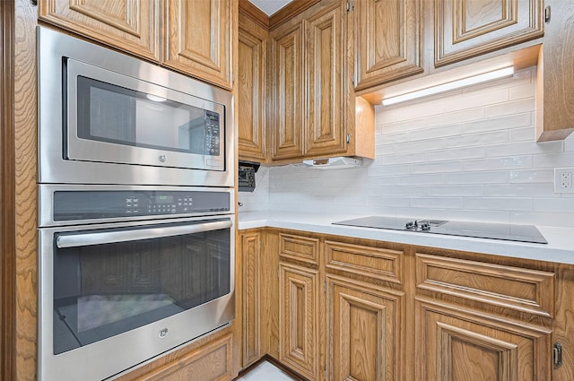 16218 Capri Dr, Jersey Village, TX 77040 - kitchen featuring appliances with stainless steel finishes, decorative backsplash, light countertops, and brown cabinets