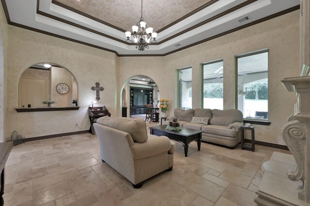 26118 Upper Beacon Pl, Montgomery, TX 77316 - living area with arched walkways, stone tile flooring, a chandelier, a raised ceiling, and ornamental molding