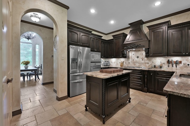 26118 Upper Beacon Pl, Montgomery, TX 77316 - kitchen featuring stainless steel appliances, crown molding, premium range hood, arched walkways, and stone tile flooring