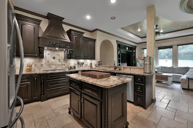 26118 Upper Beacon Pl, Montgomery, TX 77316 - kitchen featuring stainless steel appliances, crown molding, stone tile flooring, custom range hood, and backsplash