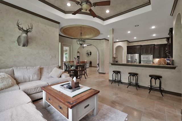 26118 Upper Beacon Pl, Montgomery, TX 77316 - living area featuring arched walkways, ornamental molding, ceiling fan, a raised ceiling, and stone tile floors