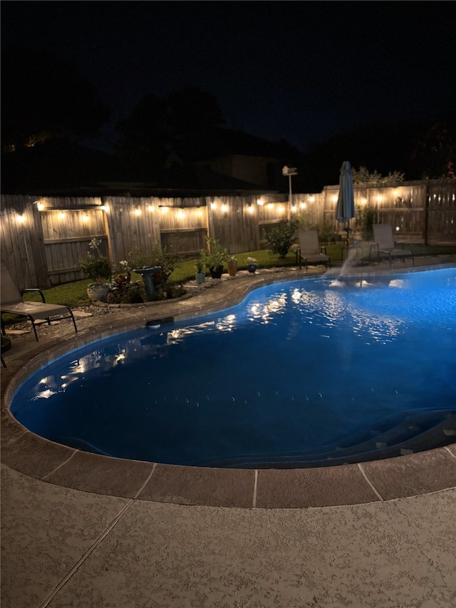 14411 Lawton Ridge Dr, Cypress, TX 77429 - pool at night featuring a fenced backyard and a patio