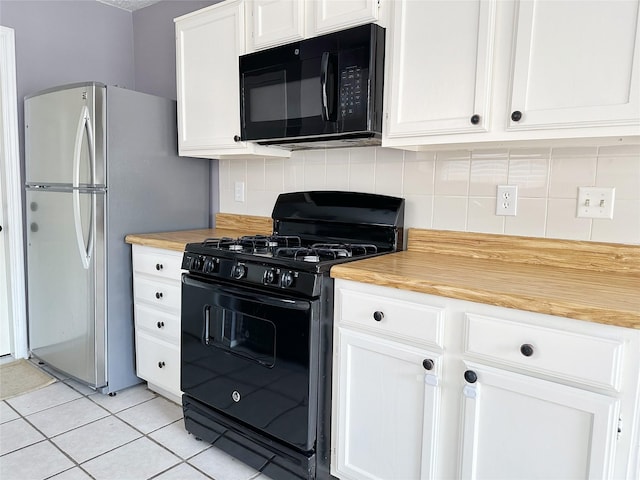kitchen with black appliances, decorative backsplash, light tile patterned floors, white cabinets, and butcher block countertops