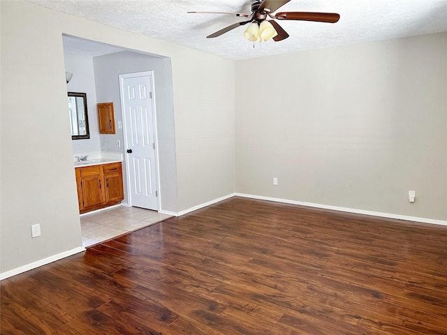 spare room with light wood-style flooring, ceiling fan, baseboards, and a textured ceiling