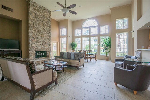 7000 Seawall Blvd Unit 1011, Galveston, TX 77551 - living room with ceiling fan, a stone fireplace, ornamental molding, a towering ceiling, and light tile patterned flooring