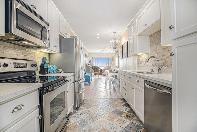 7000 Seawall Blvd Unit 1011, Galveston, TX 77551 - kitchen featuring stainless steel appliances, a sink, a chandelier, backsplash, and white cabinetry
