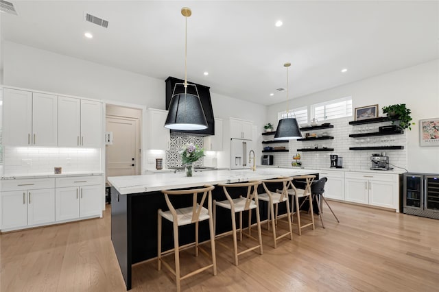 2202 Hewitt Dr, Houston, TX 77018 - kitchen featuring tasteful backsplash, open shelves, beverage cooler, a center island with sink, and white cabinets