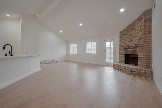 16250 Rancho Blanco Dr, Houston, TX 77083 - unfurnished living room featuring baseboards, light wood-type flooring, a fireplace, recessed lighting, and beamed ceiling