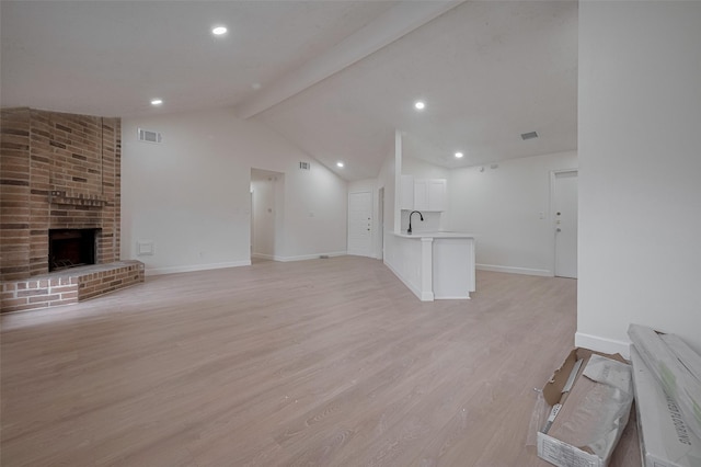 16250 Rancho Blanco Dr, Houston, TX 77083 - unfurnished living room featuring light wood-type flooring, a fireplace, baseboards, recessed lighting, and a sink