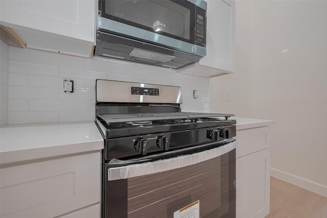 16250 Rancho Blanco Dr, Houston, TX 77083 - kitchen with appliances with stainless steel finishes, white cabinetry, decorative backsplash, light countertops, and light wood-style flooring