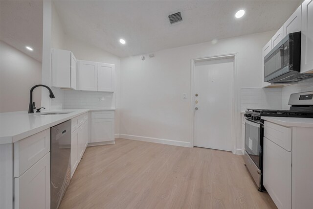 16250 Rancho Blanco Dr, Houston, TX 77083 - kitchen featuring appliances with stainless steel finishes, a sink, decorative backsplash, light wood-style flooring, and white cabinets