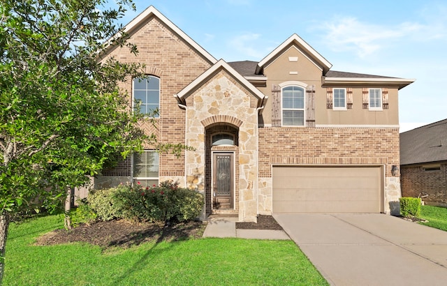 view of front of house with an attached garage, driveway, stone siding, a front yard, and brick siding
